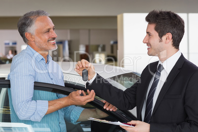 Smiling businessman giving car key to happy customer