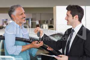 Smiling businessman giving car key to happy customer