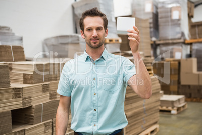 Smiling warehouse worker showing a small box