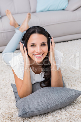 Pretty brunette lying on the rug listening to music Pretty brunette lying on the rug listening to music