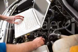 Mechanic using laptop on car