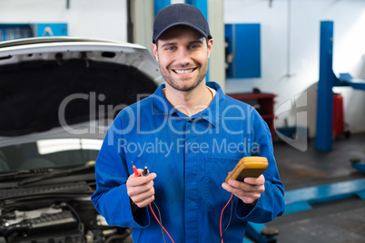 Mechanic smiling at the camera holding tool