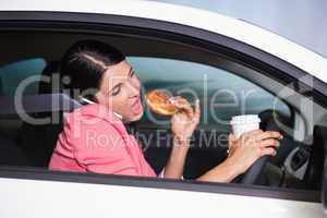Woman drinking coffee and eating donnut on phone