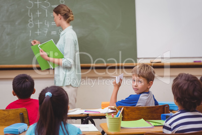 Naughty pupil about to throw paper airplane in class