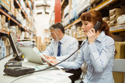 Manager working on laptop and talking on phone at desk