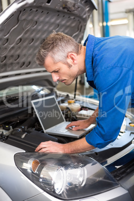 Mechanic using laptop on car