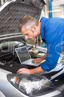 Mechanic using laptop on car