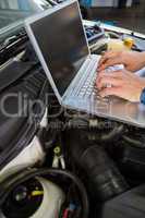 Mechanic using laptop on car