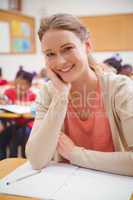 Pretty teacher smiling at camera with head in hand
