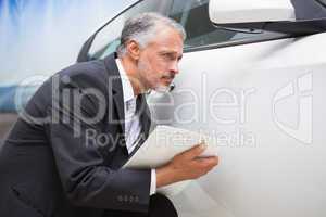 Focused businessman looking at the car body