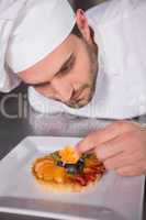 Focused baker putting flower on the pastry with fruit
