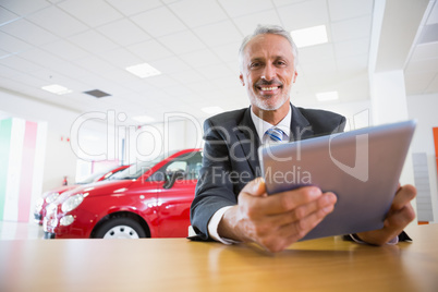 Smiling businessman using tablet at his desk