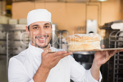 Smiling baker showing loaf of bread