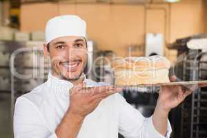 Smiling baker showing loaf of bread