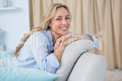 Cheerful pretty blonde sitting on couch