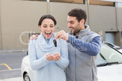 Young man surprising girlfriend with new car