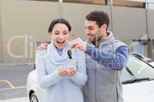 Young man surprising girlfriend with new car