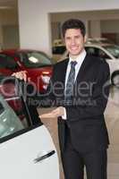 Smiling businessman showing a car for sale