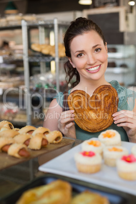 Pretty brunette holding heart shape pastry