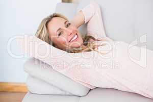 Happy blonde lying on couch with hands behind head