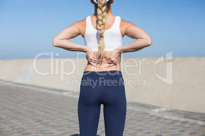 Fit blonde touching her back on the pier