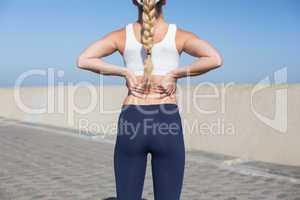 Fit blonde touching her back on the pier