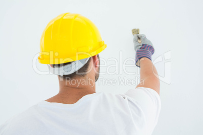 Man wearing hard hat while using paintbrush