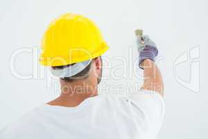 Man wearing hard hat while using paintbrush