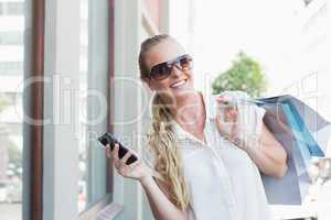 Pretty blonde texting and holding shopping bags