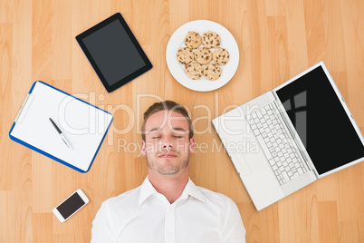 Man lying on floor surrounded by various objects at home