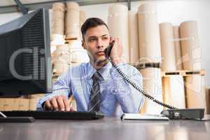 Warehouse manager using cellphone and laptop