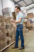 Warehouse worker checking his list on clipboard