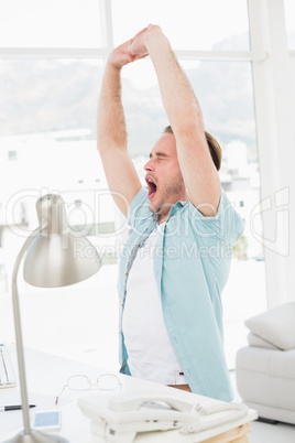 Smiling businessman stretching at desk