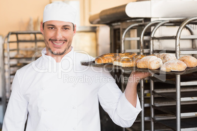 Baker holding tray of bread
