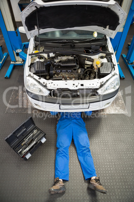 Mechanic lying and working under car