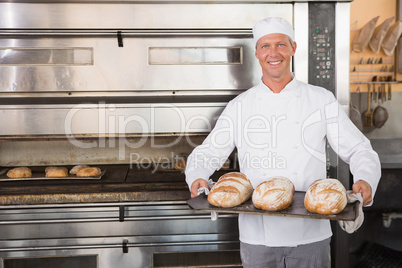Happy baker holding tray of fresh bread Happy baker holding tray of fresh bread
