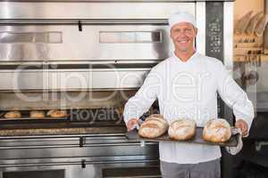 Happy baker holding tray of fresh bread