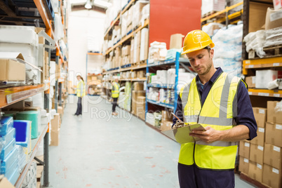 Focused warehouse worker with clipboard