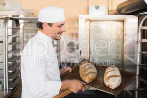 Happy baker holding tray of fresh bread