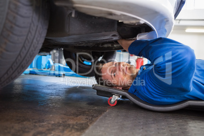 Smiling mechanic lying on trolley