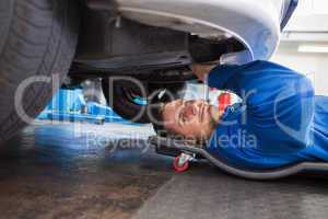 Smiling mechanic lying on trolley