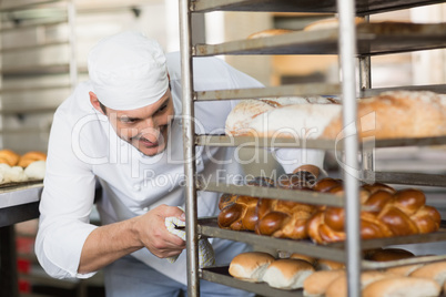 Smiling baker pushing tray of bread