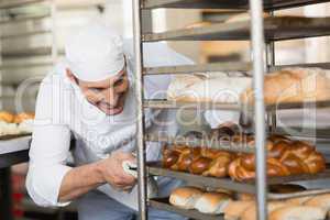 Smiling baker pushing tray of bread