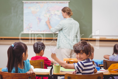 Naughty pupil about to throw paper airplane in class