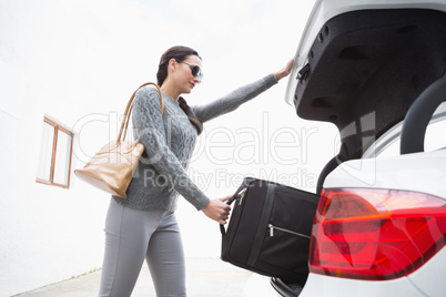 Woman pulling out a baggage of her car trunk