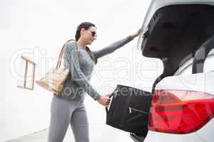 Woman pulling out a baggage of her car trunk