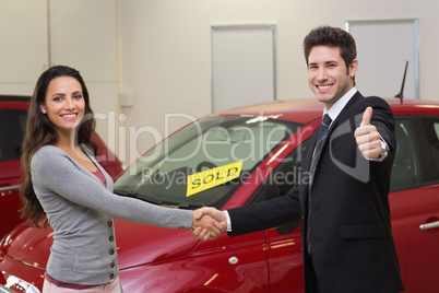 Person shaking hands in front of a sold car