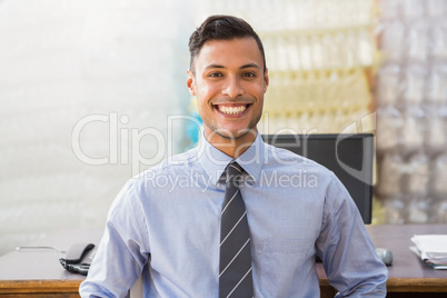 Smiling warehouse manager sitting at desk