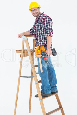 Repairman climbing ladder while holding power drill