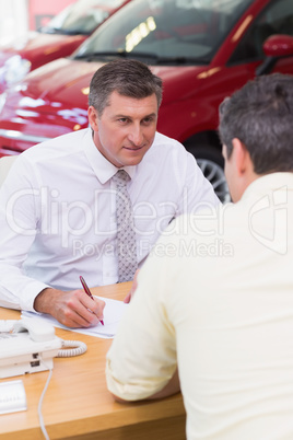 Smiling salesman writing on contract